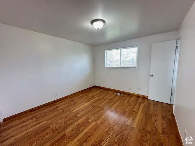 unfurnished room featuring wood finished floors, baseboards, and visible vents