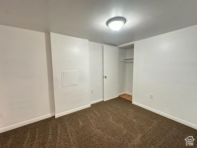 unfurnished bedroom with a closet, baseboards, and dark colored carpet