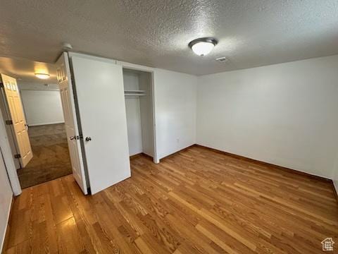 unfurnished bedroom featuring a closet, wood finished floors, and a textured ceiling