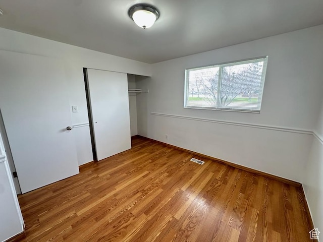unfurnished bedroom with visible vents, a closet, and light wood-style flooring