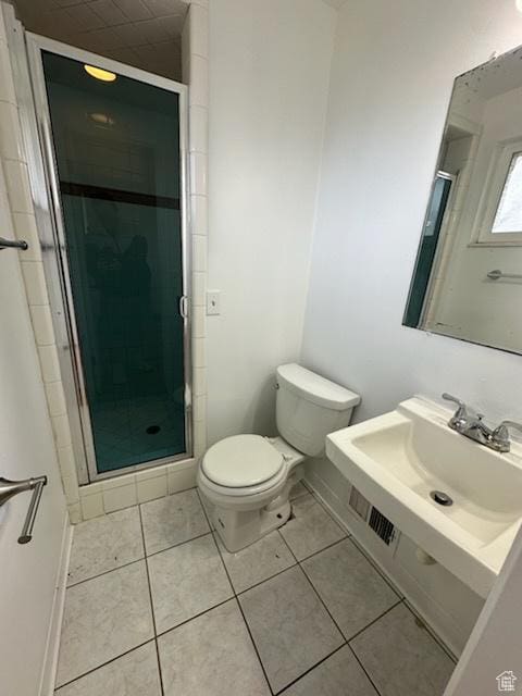 bathroom featuring baseboards, a stall shower, tile patterned floors, toilet, and a sink