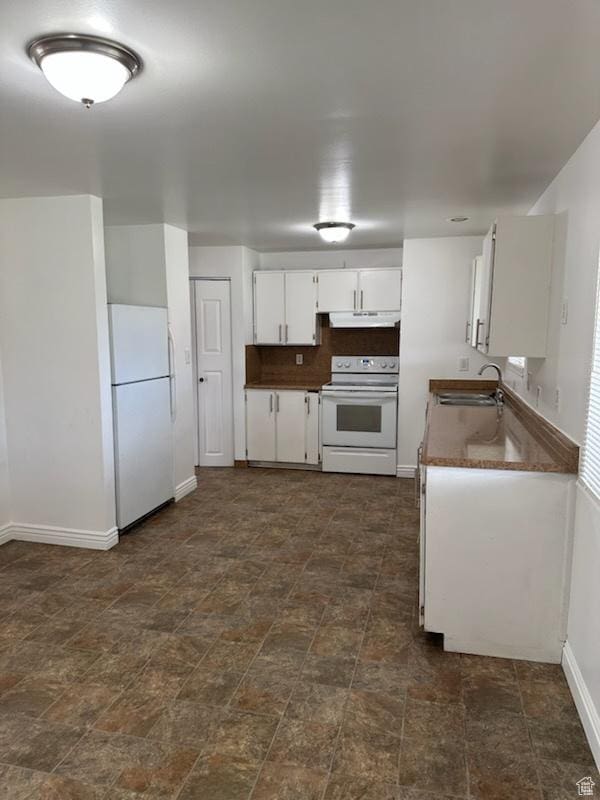 kitchen with a sink, dark countertops, white appliances, under cabinet range hood, and white cabinetry
