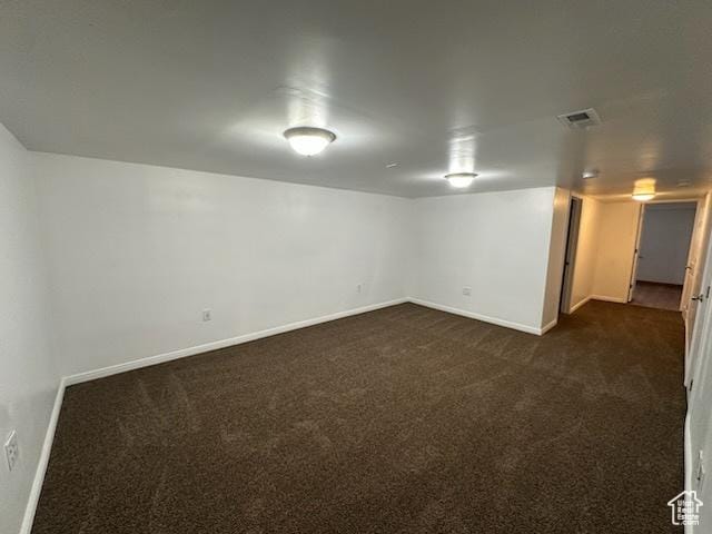 finished below grade area featuring visible vents, baseboards, and dark colored carpet