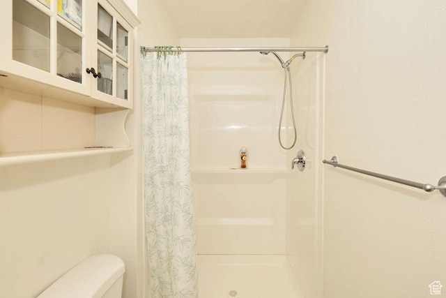 full bath featuring a shower stall and toilet