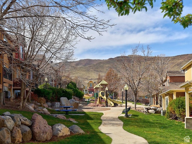 view of home's community with a yard, a mountain view, and playground community