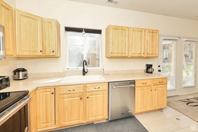 kitchen featuring a healthy amount of sunlight, a sink, light brown cabinetry, and appliances with stainless steel finishes