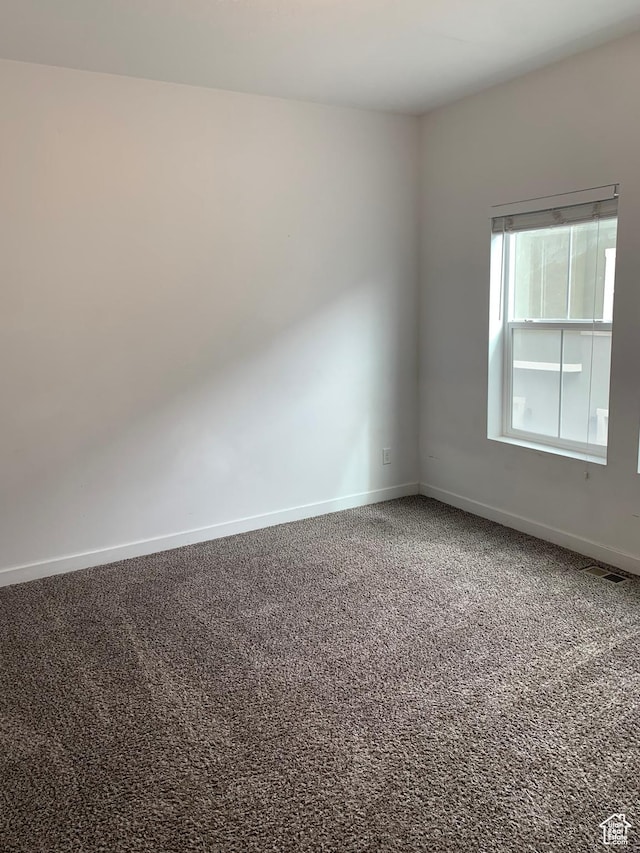unfurnished room with carpet flooring, visible vents, and baseboards
