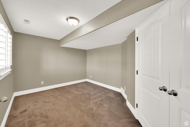 below grade area with carpet flooring, visible vents, and baseboards