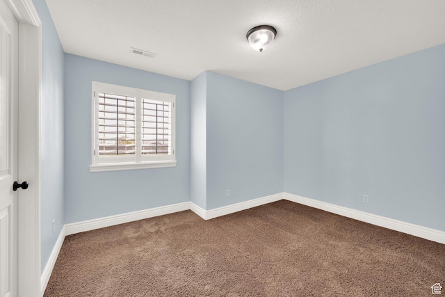 empty room featuring dark carpet, baseboards, and visible vents