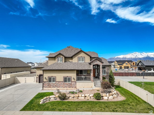 view of front facade with a mountain view, stone siding, stucco siding, a gate, and fence private yard