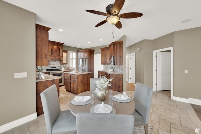 dining room with baseboards, arched walkways, stone tile flooring, a ceiling fan, and recessed lighting