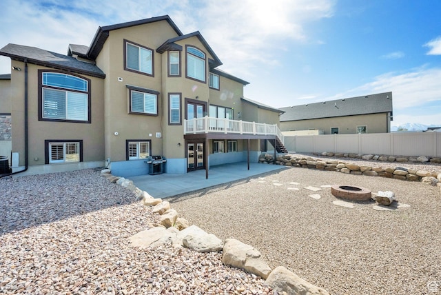 back of house featuring stucco siding, french doors, a patio area, an outdoor fire pit, and fence