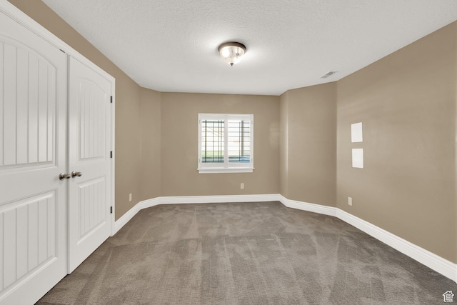 carpeted spare room featuring visible vents, baseboards, and a textured ceiling