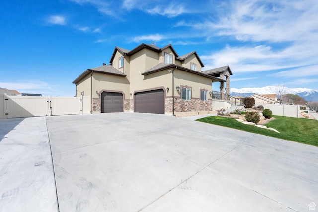 view of side of property featuring a yard, stucco siding, a gate, a garage, and concrete driveway