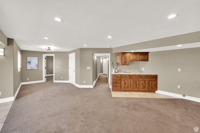 kitchen featuring baseboards, light carpet, recessed lighting, light countertops, and brown cabinetry