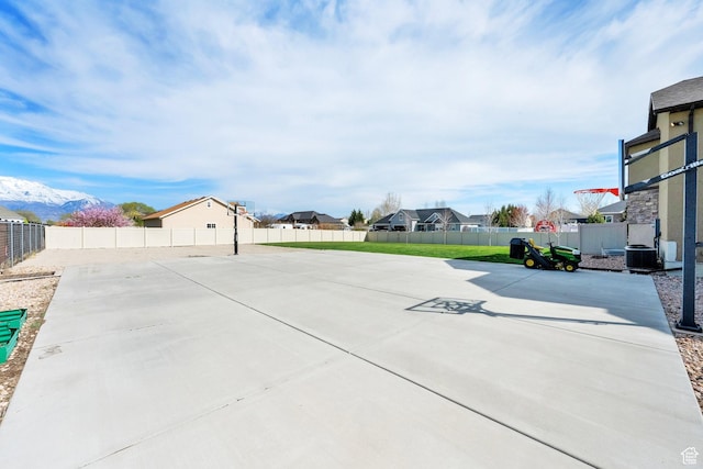 view of patio / terrace with central AC, basketball hoop, fence, and a residential view