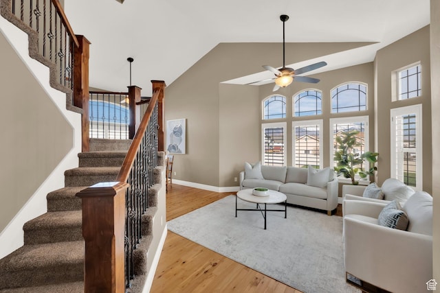 living area with high vaulted ceiling, a wealth of natural light, a ceiling fan, and stairs