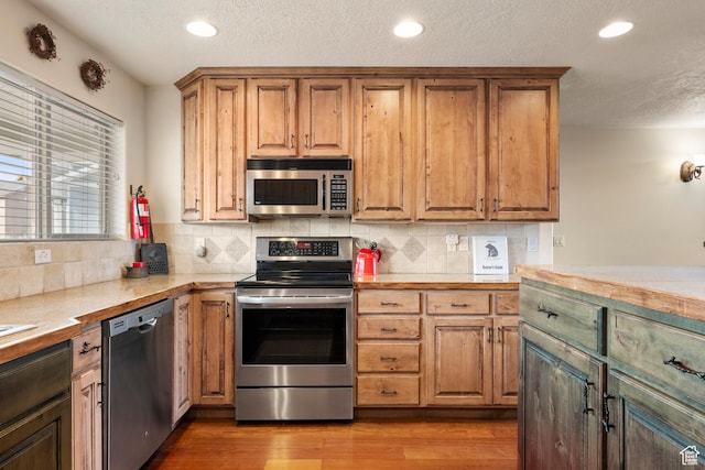 17 Wedge Way, Garden City, UT 84028 - kitchen with appliances with stainless steel finishes, light countertops, a textured ceiling, tasteful backsplash, and wood finished floors