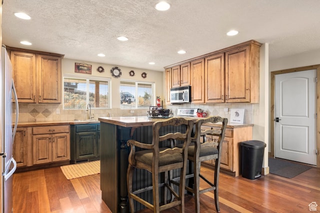 17 Wedge Way, Garden City, UT 84028 - kitchen with appliances with stainless steel finishes, dark wood-type flooring, a kitchen bar, decorative backsplash, and a textured ceiling