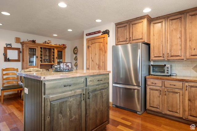 17 Wedge Way, Garden City, UT 84028 - kitchen with freestanding refrigerator, a center island, wood finished floors, recessed lighting, and backsplash