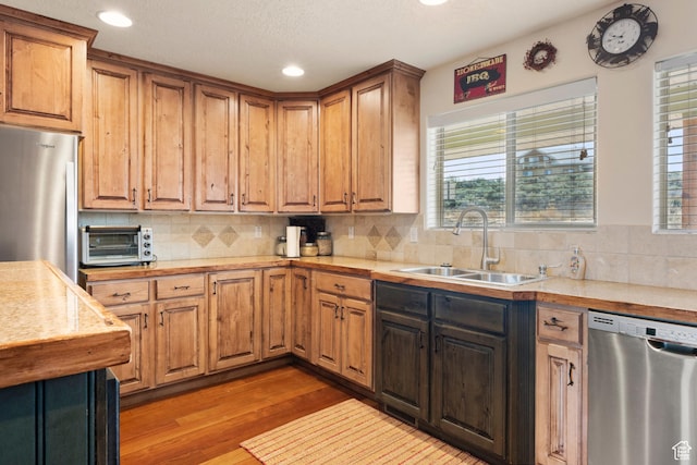 17 Wedge Way, Garden City, UT 84028 - kitchen featuring stainless steel appliances, a sink, light countertops, light wood-style flooring, and decorative backsplash