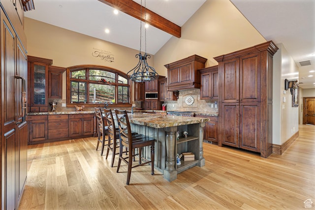 2499 River Meadows Ln, Midway, UT 84049 - kitchen with stainless steel microwave, light wood-style flooring, tasteful backsplash, beamed ceiling, and a kitchen island with sink