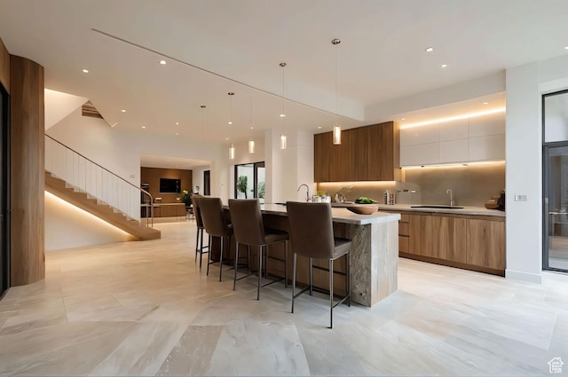 2499 River Meadows Ln, Midway, UT 84049 - kitchen with modern cabinets, a large island with sink, brown cabinets, light countertops, and a breakfast bar