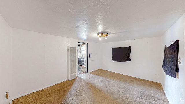 carpeted empty room with a textured ceiling and baseboards