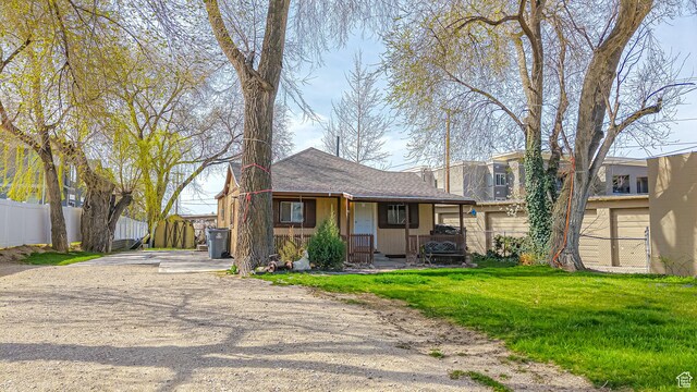 view of front of home with covered porch, fence, a front lawn, and dirt driveway