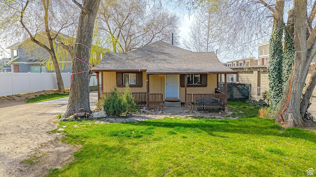 exterior space featuring a yard, fence, and a shingled roof
