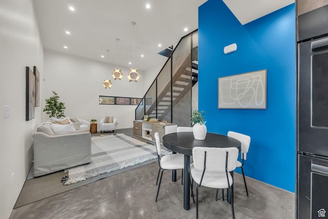 dining space with concrete floors, recessed lighting, a high ceiling, and stairway