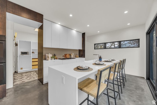 kitchen featuring finished concrete flooring, modern cabinets, white cabinetry, recessed lighting, and light countertops