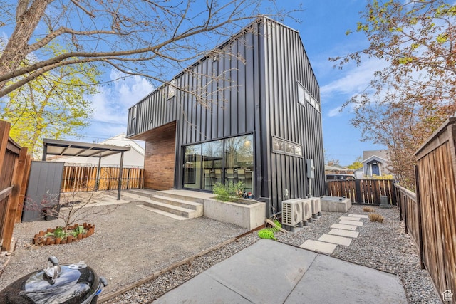 rear view of house with a patio, board and batten siding, and a fenced backyard