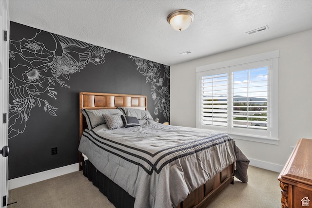 bedroom with carpet, a textured ceiling, an accent wall, visible vents, and baseboards