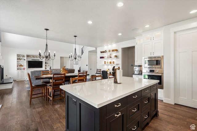 kitchen with a notable chandelier, open floor plan, white cabinets, dark wood finished floors, and appliances with stainless steel finishes