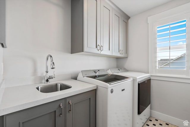 laundry room with a sink, baseboards, cabinet space, and separate washer and dryer