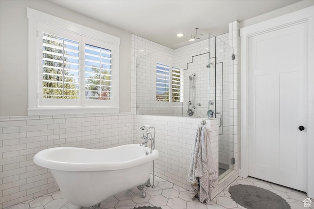 bathroom featuring a shower stall, tile patterned floors, a freestanding tub, and tile walls