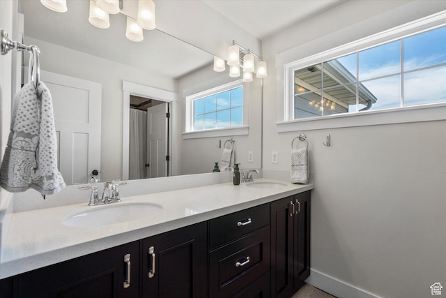 bathroom with a sink, baseboards, and double vanity
