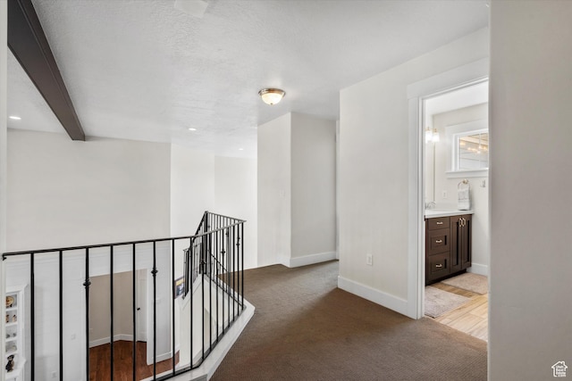 hall with light colored carpet, baseboards, and an upstairs landing