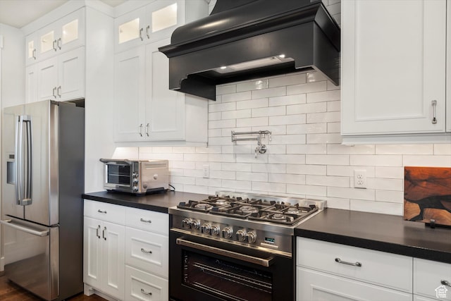 kitchen with white cabinetry, dark countertops, exhaust hood, and stainless steel appliances
