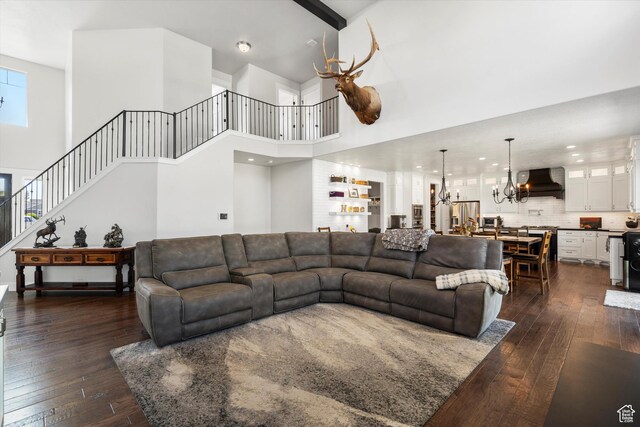 living area featuring a chandelier, stairway, a towering ceiling, and dark wood finished floors