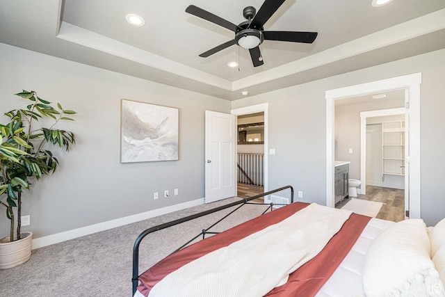 bedroom with baseboards, recessed lighting, connected bathroom, and a raised ceiling