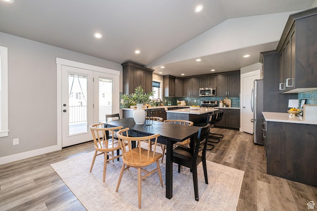 dining space with recessed lighting, baseboards, wood finished floors, and vaulted ceiling
