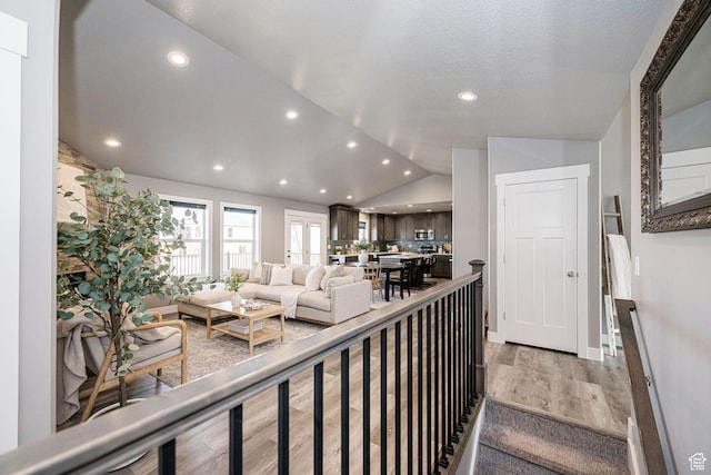 living room featuring light wood-style floors, baseboards, lofted ceiling, and recessed lighting