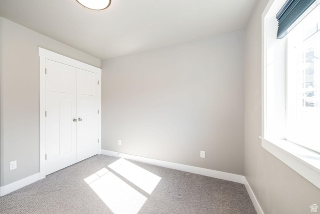 unfurnished bedroom featuring multiple windows, baseboards, and carpet floors