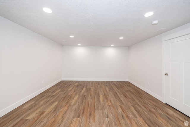 basement featuring recessed lighting, baseboards, a textured ceiling, and wood finished floors