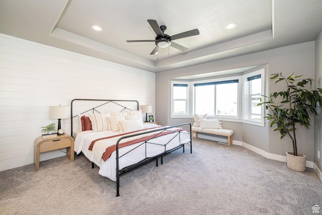 bedroom with a tray ceiling, light colored carpet, and recessed lighting