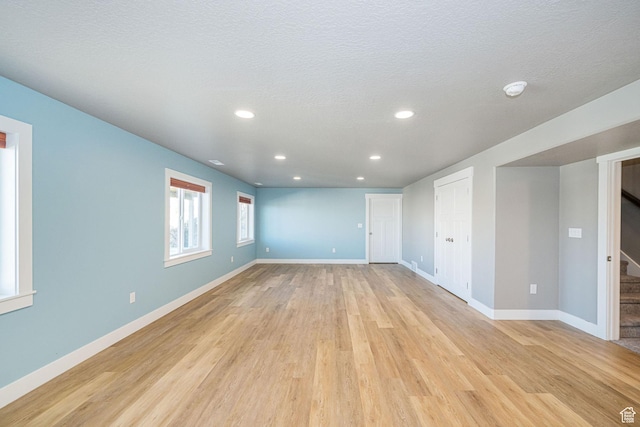 spare room with baseboards, recessed lighting, a textured ceiling, stairs, and light wood finished floors