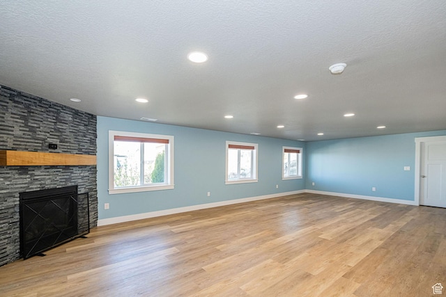 unfurnished living room with baseboards, light wood finished floors, recessed lighting, and a fireplace