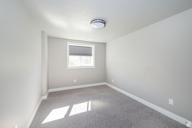 carpeted empty room featuring baseboards and a textured ceiling